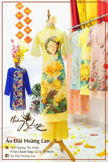 Áo dài cách tân vàng in hình hoa cúc và áo trẻ em xanh dương, khung ảnh có tên tiệm.