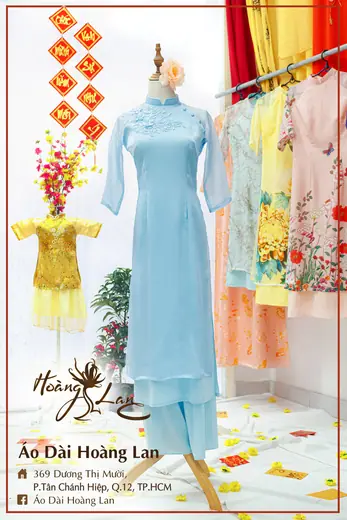 Áo dài cách tân xanh nhạt phối quần cùng màu và áo trẻ em vàng, khung ảnh có tên tiệm.