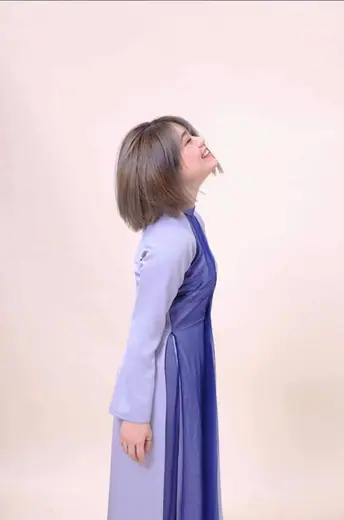 Một cô gái mặc áo dài tím nhạt phối tà xanh tím than, nhìn nghiêng.