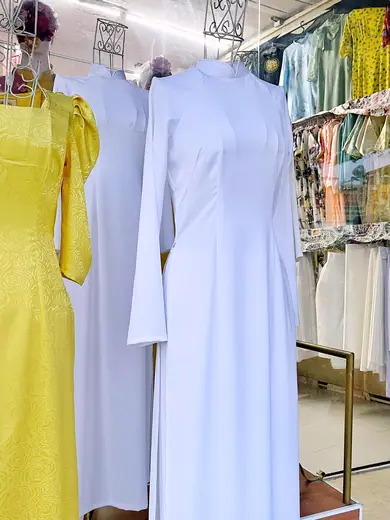 Áo dài vàng và áo dài trắng nữ sinh trên ma-nơ-canh trong tiệm.