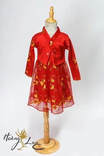 Áo dài bé gái đỏ phối chân váy voan trên ma-nơ-canh nhỏ, có logo tiệm.