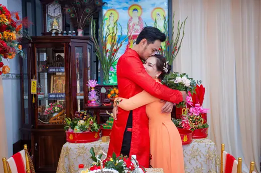 Cô dâu chú rể mặc áo dài đỏ ôm nhau trong lễ gia tiên.