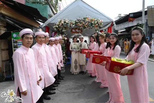 Dàn bưng quả nam nữ mặc áo dài hồng xếp hàng chờ làm lễ.